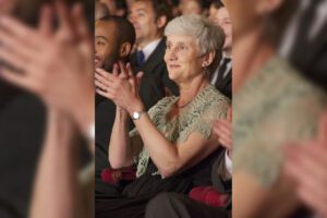 A woman clapping in front of other people.