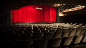 A theater with rows of seats and red curtains.
